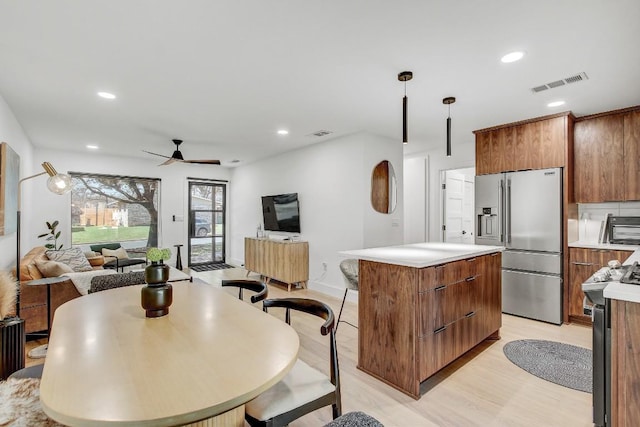 kitchen with visible vents, brown cabinets, open floor plan, a center island, and appliances with stainless steel finishes