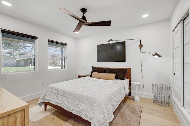 bedroom with a closet, recessed lighting, light wood-style flooring, and baseboards