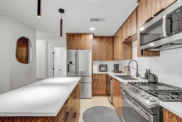 kitchen with a sink, visible vents, brown cabinets, and appliances with stainless steel finishes