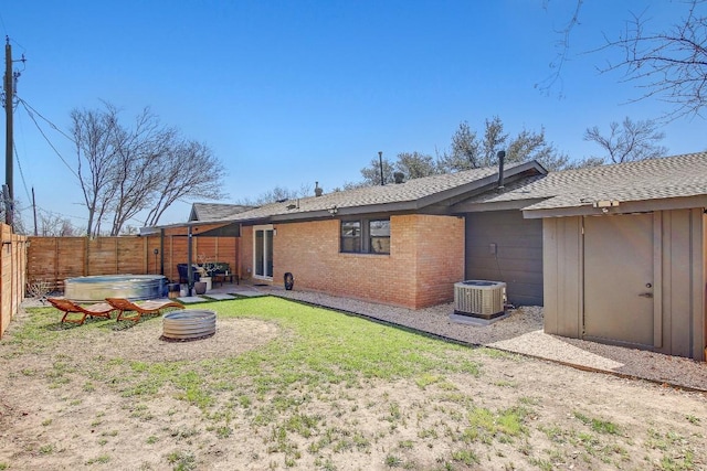 back of property featuring a fenced backyard, a yard, cooling unit, brick siding, and a patio area