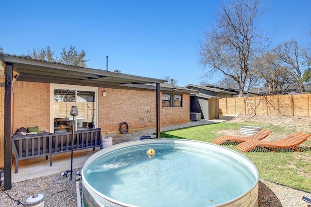 rear view of property featuring brick siding, cooling unit, a jacuzzi, and fence