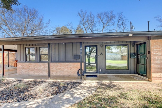 entrance to property with brick siding and board and batten siding