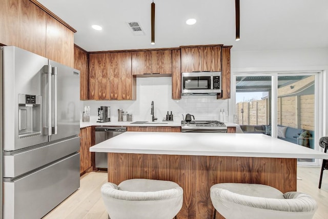 kitchen with visible vents, light wood-type flooring, light countertops, stainless steel appliances, and a sink