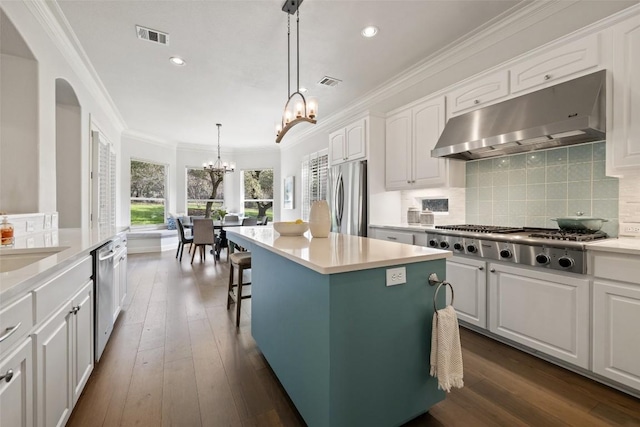 kitchen with visible vents, an inviting chandelier, appliances with stainless steel finishes, under cabinet range hood, and crown molding