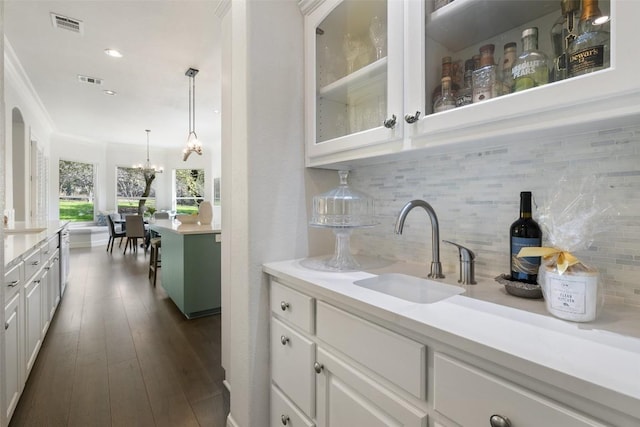 bar featuring a sink, dark wood-style flooring, visible vents, a notable chandelier, and decorative backsplash