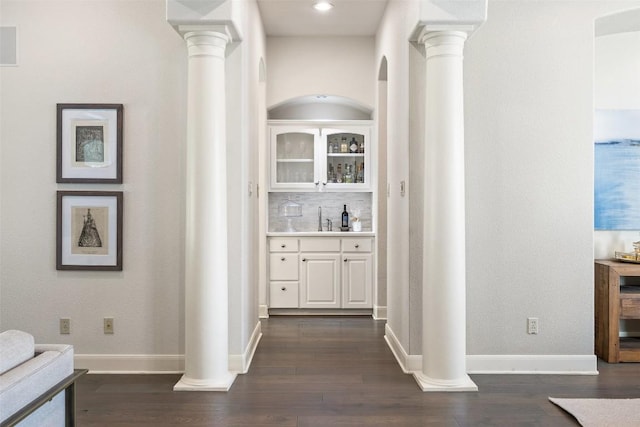 hall with a sink, dark wood-style floors, and ornate columns