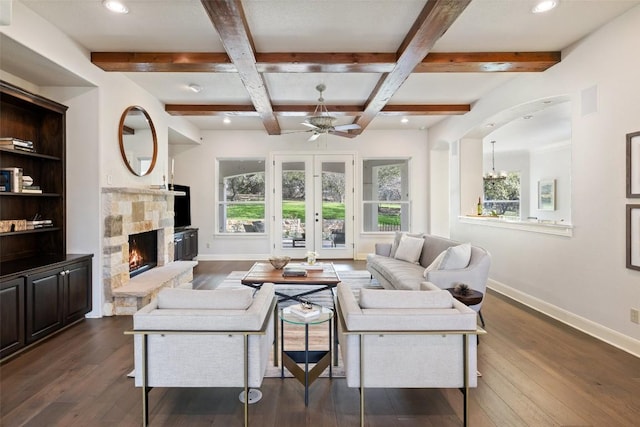 living room featuring a stone fireplace, dark wood-style floors, baseboards, and coffered ceiling