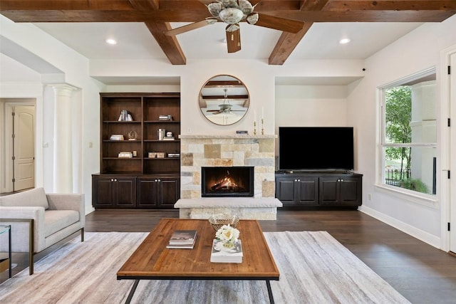 unfurnished living room with baseboards, beamed ceiling, a stone fireplace, coffered ceiling, and dark wood-style flooring