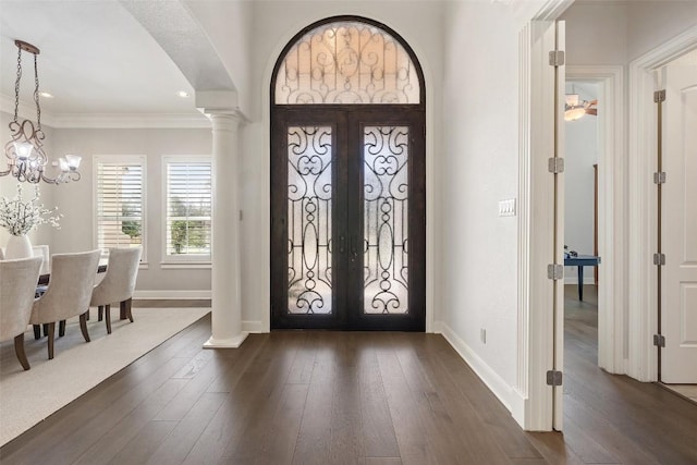 foyer entrance with a notable chandelier, ornamental molding, dark wood finished floors, french doors, and baseboards