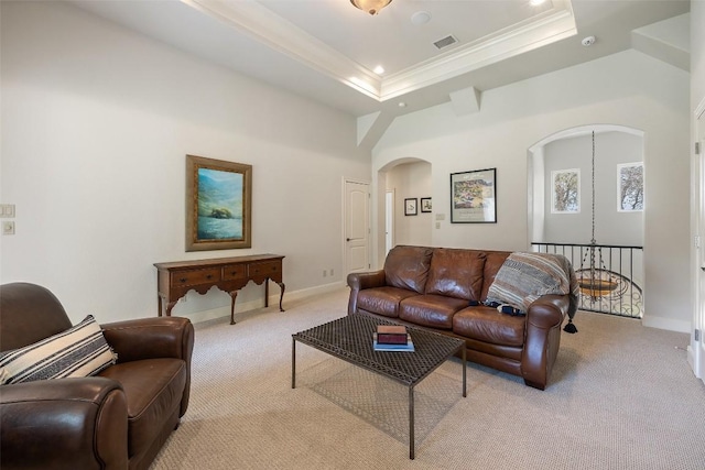 living room with crown molding, baseboards, light colored carpet, a tray ceiling, and arched walkways