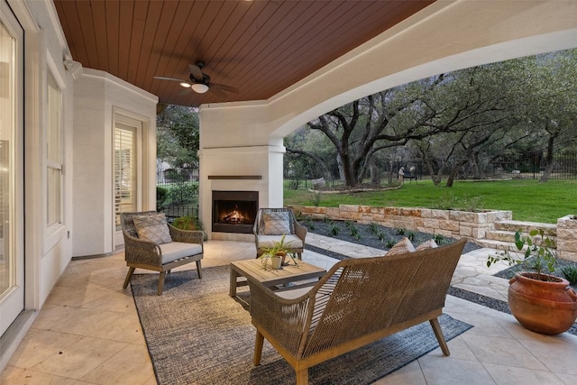 view of patio / terrace with a ceiling fan and an outdoor living space with a fireplace