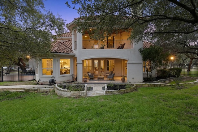 rear view of house with a balcony, fence, stucco siding, a tiled roof, and a patio area