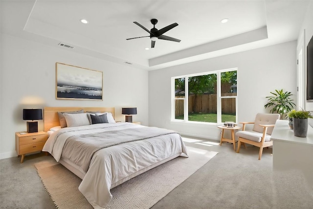 bedroom with a tray ceiling, carpet flooring, recessed lighting, and visible vents