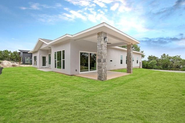 back of property with a yard, stucco siding, and a patio area