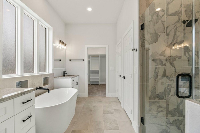 full bath with a stall shower, recessed lighting, vanity, a freestanding bath, and a spacious closet