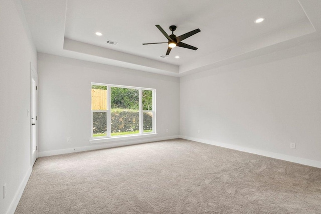 carpeted spare room with visible vents, baseboards, and a tray ceiling