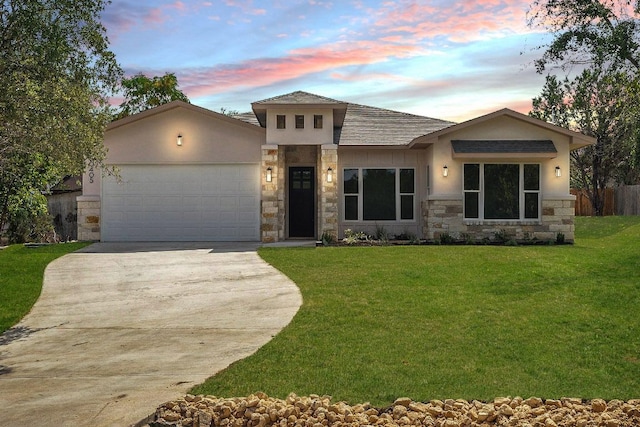 view of front of house featuring concrete driveway, stucco siding, a yard, stone siding, and an attached garage