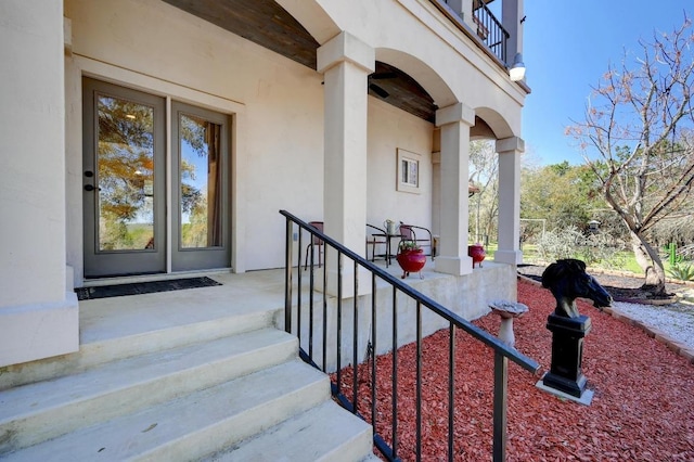 view of exterior entry with stucco siding and a balcony