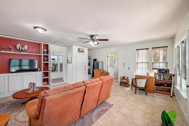 living room featuring attic access, light tile patterned flooring, baseboards, and ceiling fan