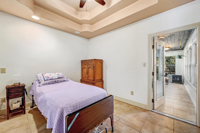 bedroom featuring light tile patterned floors, ceiling fan, a raised ceiling, and baseboards