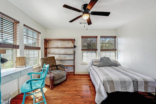 bedroom with multiple windows, wood finished floors, visible vents, and ceiling fan