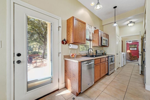 kitchen featuring a sink, stainless steel appliances, light tile patterned flooring, brown cabinetry, and light countertops