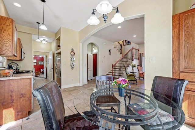 dining space with light tile patterned floors, baseboards, arched walkways, and stairs