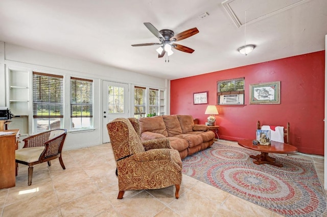 living room with built in features, attic access, and a ceiling fan