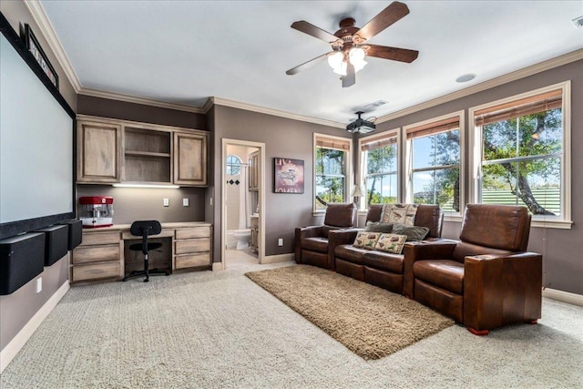 living area with a ceiling fan, crown molding, baseboards, light colored carpet, and built in study area