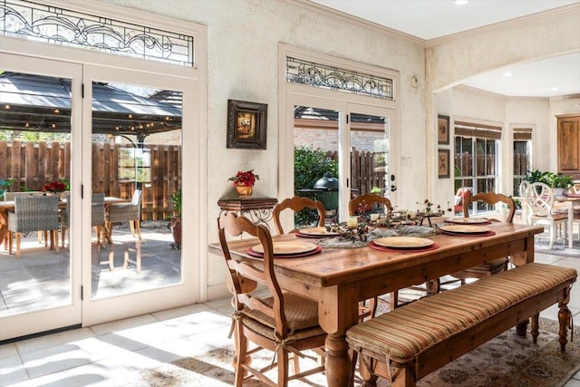 dining space with arched walkways, ornamental molding, and a textured wall