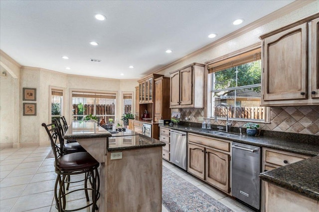 kitchen with a center island, ornamental molding, stainless steel dishwasher, light tile patterned flooring, and a sink