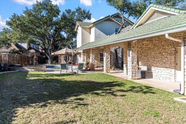 back of property with stone siding, a lawn, a patio, and fence