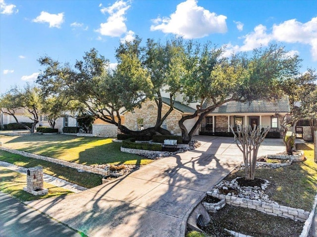 view of front of property featuring stone siding, driveway, and a front lawn