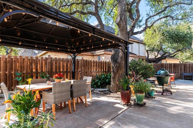 view of patio with a gazebo, outdoor dining area, and fence