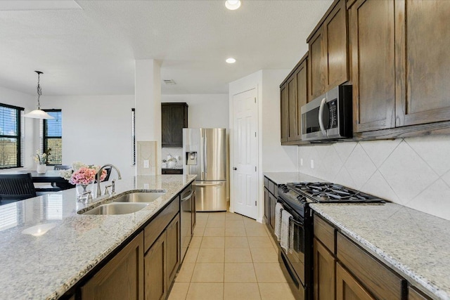 kitchen with a sink, appliances with stainless steel finishes, light tile patterned flooring, decorative backsplash, and hanging light fixtures