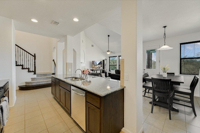 kitchen with visible vents, a sink, light stone counters, stainless steel dishwasher, and open floor plan