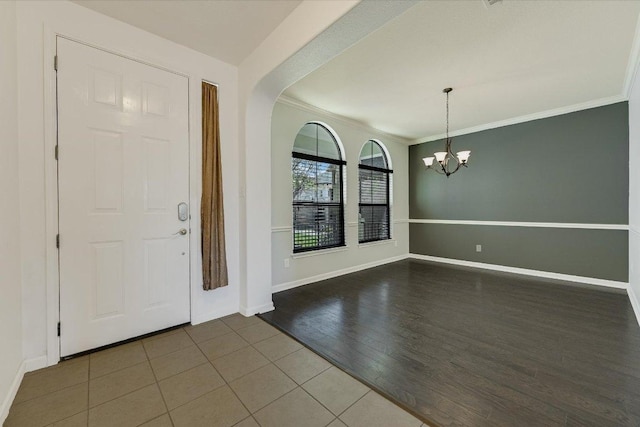 entrance foyer with a notable chandelier, wood finished floors, baseboards, and ornamental molding