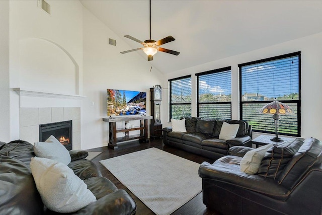 living area featuring a tiled fireplace, wood finished floors, visible vents, and high vaulted ceiling