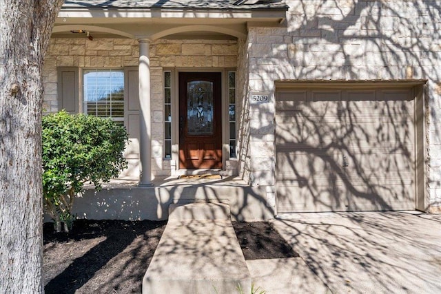 entrance to property featuring stone siding, a shingled roof, and a garage