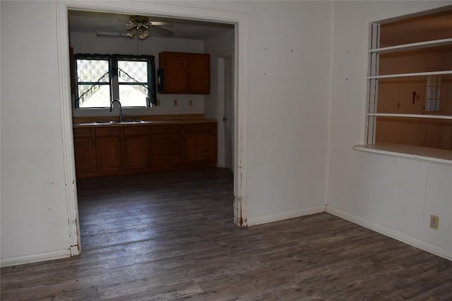 unfurnished dining area with ceiling fan, dark wood-style floors, baseboards, and a sink