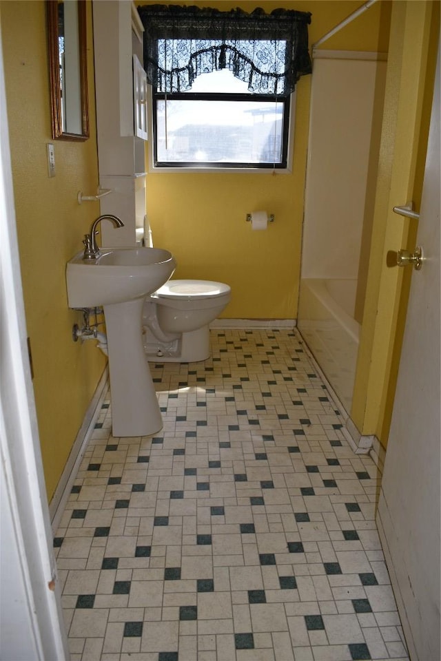 bathroom featuring toilet, tub / shower combination, and baseboards