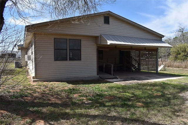 back of property featuring metal roof, a lawn, and central AC