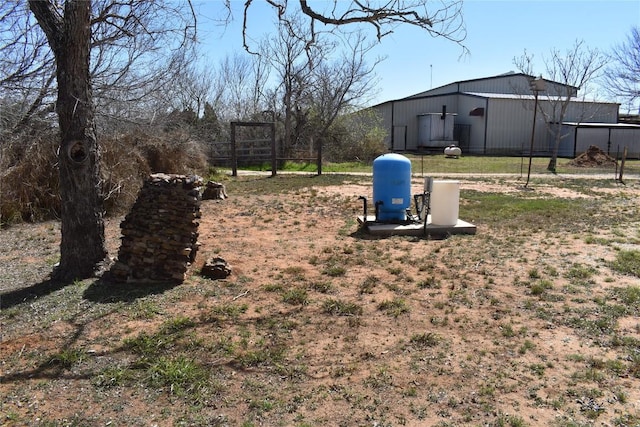 view of yard featuring an outdoor structure, fence, and a pole building