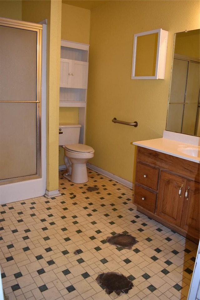 bathroom featuring a stall shower, toilet, vanity, and baseboards