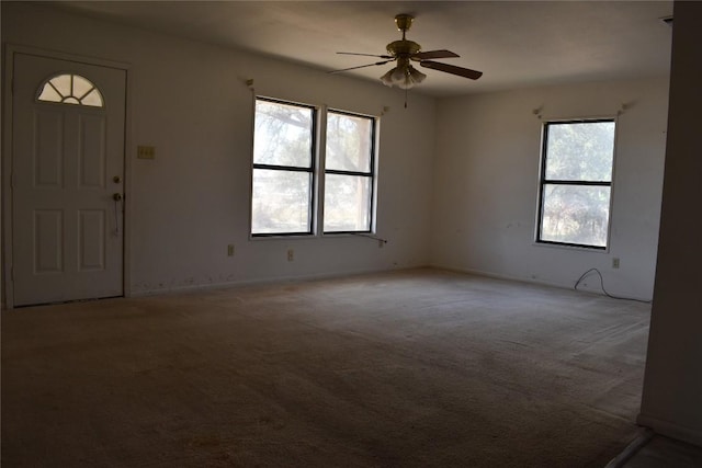 empty room featuring a ceiling fan and carpet