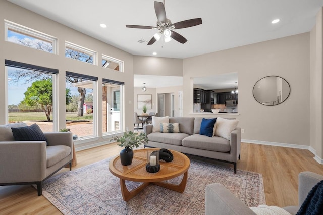 living room with visible vents, baseboards, light wood-style flooring, recessed lighting, and ceiling fan with notable chandelier