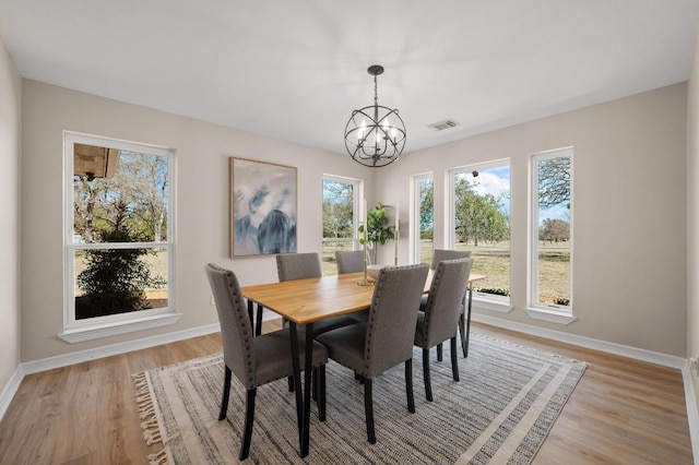 dining space with visible vents, light wood-style flooring, baseboards, and an inviting chandelier