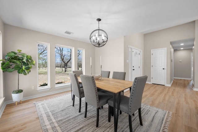 dining room with an inviting chandelier, light wood-style floors, visible vents, and baseboards