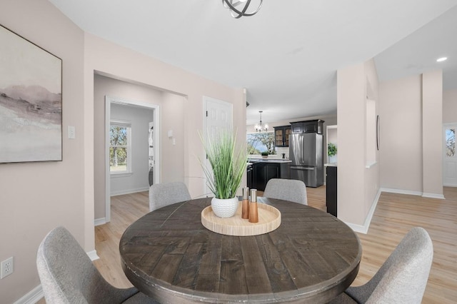 dining area featuring baseboards, a notable chandelier, and light wood finished floors