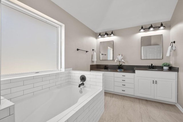 full bath featuring double vanity, a bath, and a sink